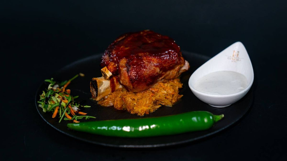 Ciolan de Porc Caramelizat pe Pat de Varză Călită și Sos de Hrean cu Smântână