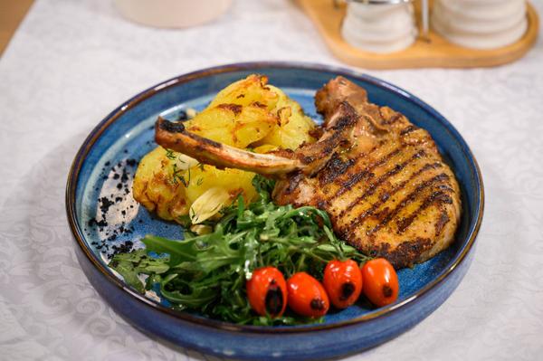 Tomahawk de porc servit cu cartofi zdrobiți și murături de casă